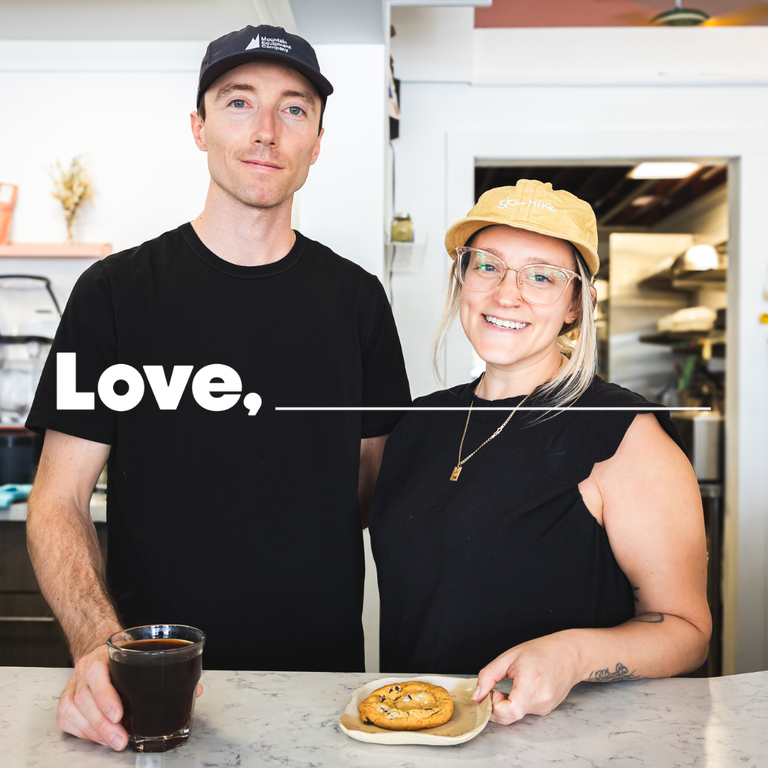 A man and woman stand behind the counter at a cafe